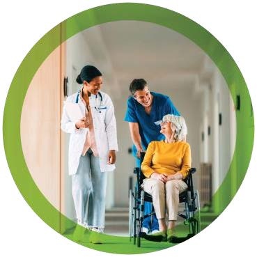 Care team members accompanying a patient in a wheelchair.